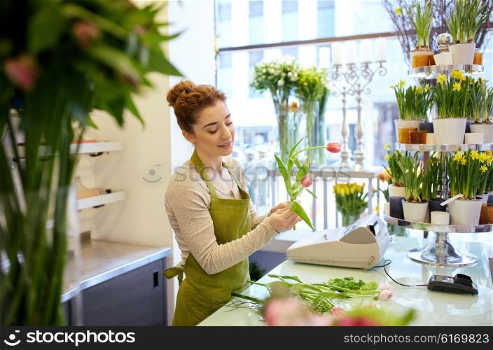 people, business, sale and floristry concept - happy smiling florist woman making tulip bunch at flower shop