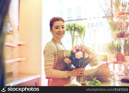 people, business, sale and floristry concept - happy smiling florist woman making bunch at flower shop. smiling florist woman making bunch at flower shop