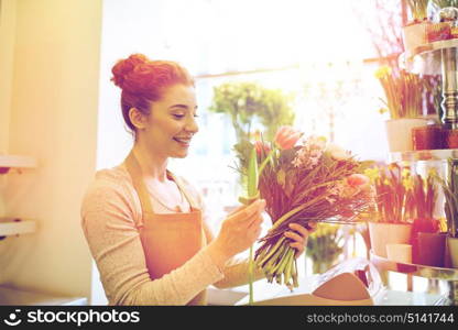 people, business, sale and floristry concept - happy smiling florist woman making bunch at flower shop. smiling florist woman making bunch at flower shop