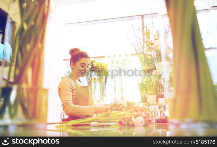 people, business, sale and floristry concept - happy smiling florist woman making bunch at flower shop. smiling florist woman making bunch at flower shop