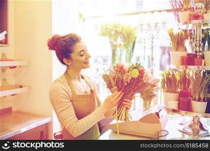 people, business, sale and floristry concept - happy smiling florist woman making bunch at flower shop. smiling florist woman making bunch at flower shop