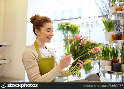 people, business, sale and floristry concept - happy smiling florist woman making bunch at flower shop