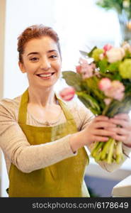 people, business, sale and floristry concept - happy smiling florist woman making bunch at flower shop