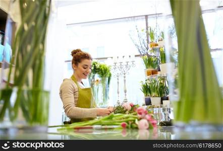 people, business, sale and floristry concept - happy smiling florist woman making bunch at flower shop