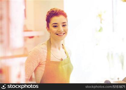 people, business, sale, gardening and floristry concept - happy smiling florist woman or gardener at flower shop. smiling florist woman or gardener at flower shop