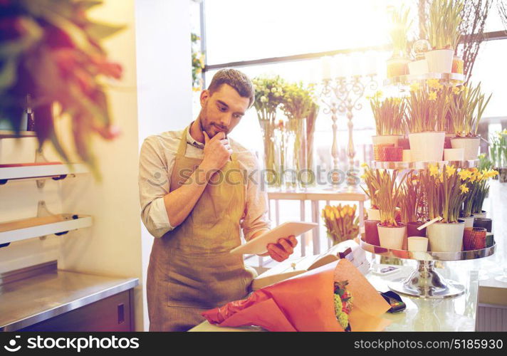 people, business, technology, sale and floristry and concept - florist man with tablet pc computer thinking at flower shop counter. man with tablet pc computer at flower shop