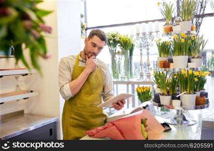 people, business, technology, sale and floristry and concept - florist man with tablet pc computer thinking at flower shop counter