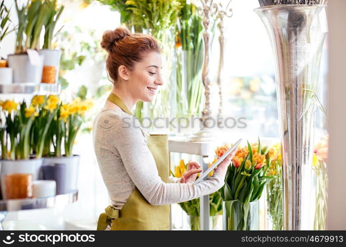 people, business, technology, sale and floristry and concept - happy smiling florist woman with tablet pc computer at flower shop