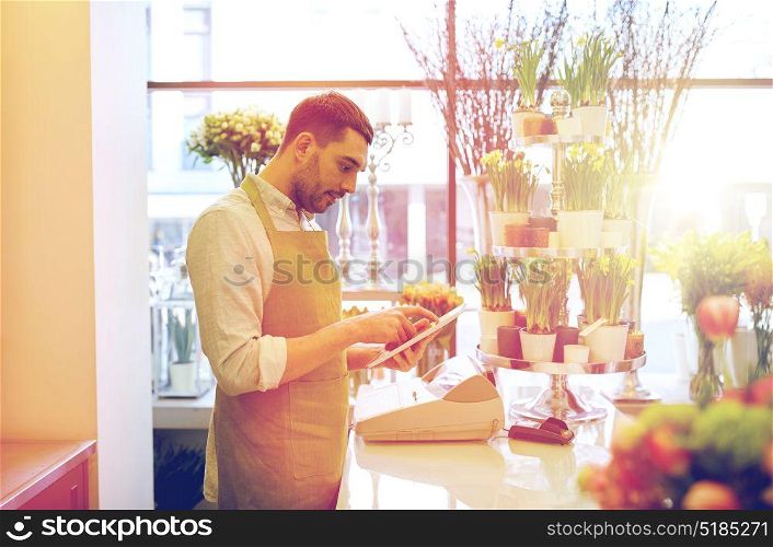 people, business, technology, sale and floristry and concept - happy smiling florist man with tablet pc computer at flower shop counter. man with tablet pc computer at flower shop