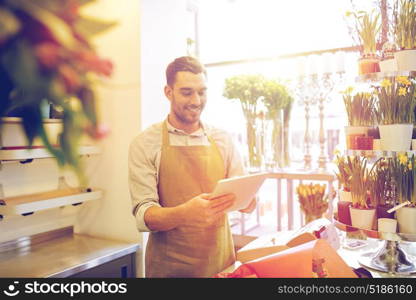 people, business, technology, sale and floristry and concept - happy smiling florist man with tablet pc computer at flower shop counter. man with tablet pc computer at flower shop