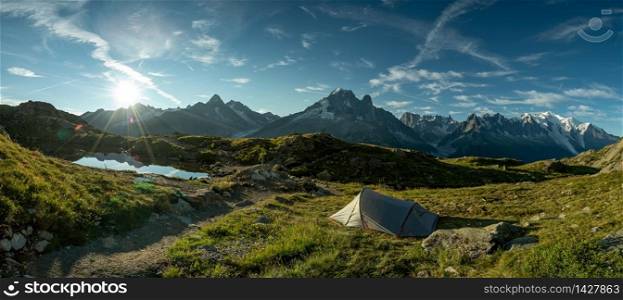 People camping in the mountains with a tent in front of the Mont Blanc in the French Alps.
