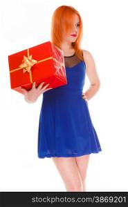 People celebrating holidays, love and happiness concept - red head girl in blue dress looked pensively holds red gift box studio shot isolated. Time gifts