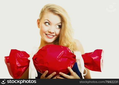 People celebrating holidays, love and happiness concept - smiling girl holding big red gift candy shaped studi shot on gray