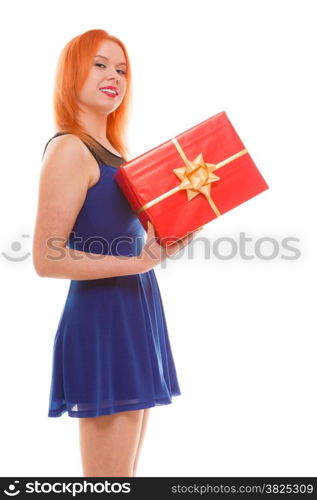 People celebrating holidays, love and happiness concept - smiling red head girl in blue dress holds red gift box studio shot isolated. Time gifts