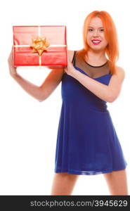 People celebrating holidays, love and happiness concept - smiling red head girl in blue dress holds red gift box studio shot isolated. Time gifts