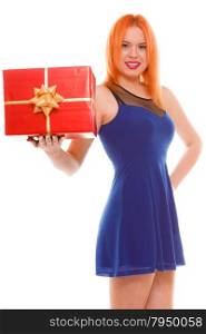 People celebrating holidays, love and happiness concept - smiling red head girl in blue dress holds red gift box studio shot isolated. Time gifts