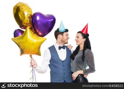 people, celebration and holidays concept - happy couple with party caps and balloons. happy couple with party caps and balloons