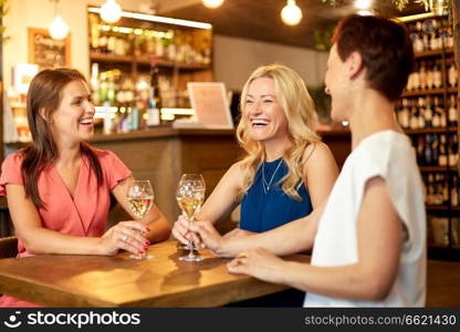 people, celebration and lifestyle concept - happy women drinking wine and talking at bar or restaurant. happy women drinking wine at bar or restaurant