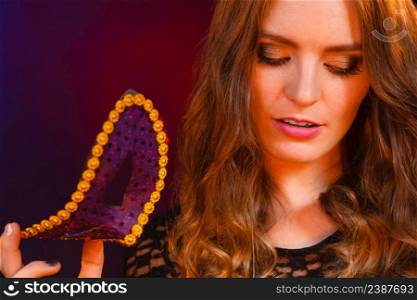 People celebration concept. Masquerade. Beautiful girl holding carnival mysterious mask on dark. Closeup woman face with carnival mask on dark