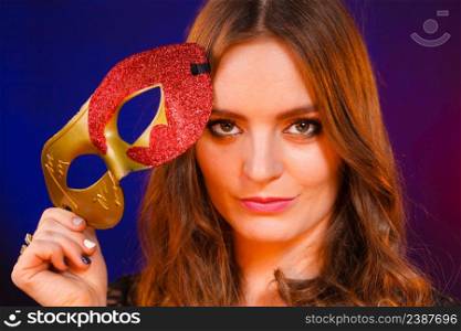 People celebration concept. Masquerade. Beautiful girl holding carnival mysterious mask on dark. Closeup woman face with carnival mask on dark