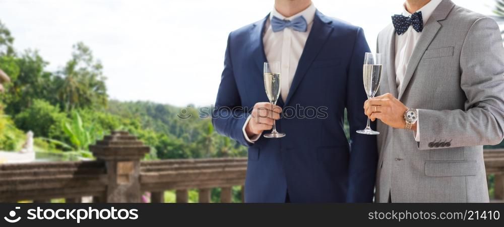people, celebration, homosexuality, same-sex marriage and love concept - close up of happy married male gay couple drinking sparkling wine from glasses on wedding over balcony and nature background