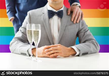 people, celebration, homosexuality, same-sex marriage and love concept - close up of happy married male gay couple with sparkling wine glasses on wedding over rainbow flag background