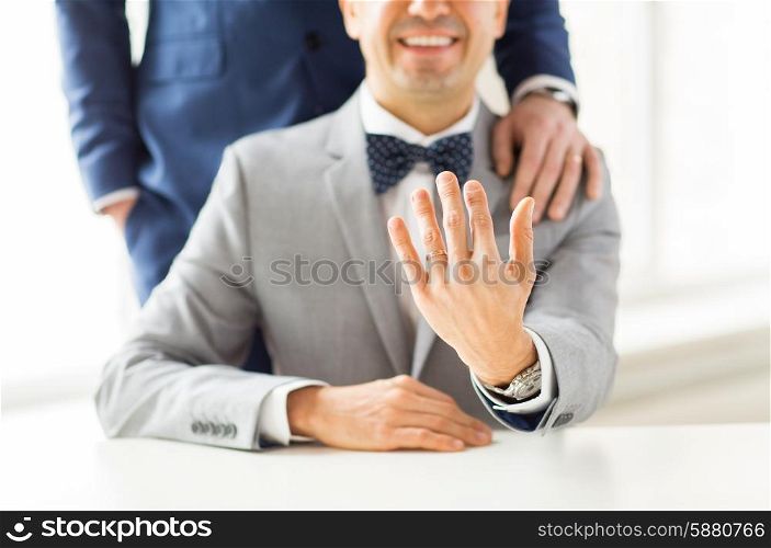 people, celebration, homosexuality, same-sex marriage and love concept - close up of male gay couple with wedding rings on putting hand on shoulder
