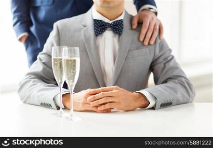 people, celebration, homosexuality, same-sex marriage and love concept - close up of happy married male gay couple in suits and bow-ties with sparkling wine glasses putting hand on shoulder on wedding