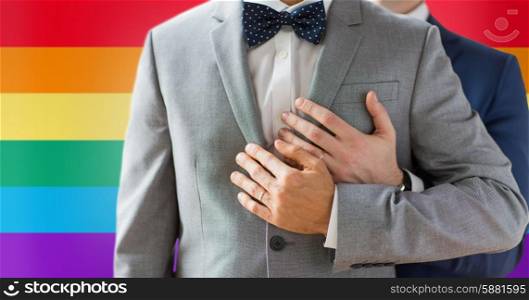 people, celebration, homosexuality, same-sex marriage and love concept - close up of happy male gay couple with wedding rings hugging over rainbow flag background
