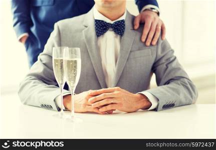 people, celebration, homosexuality, same-sex marriage and love concept - close up of happy married male gay couple in suits and bow-ties with sparkling wine glasses putting hand on shoulder on wedding