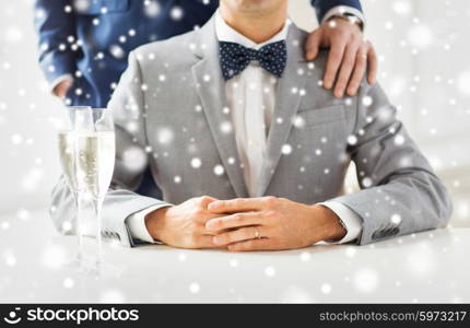 people, celebration, homosexuality, same-sex marriage and love concept - close up of married male gay couple in suits with sparkling wine glasses putting hand on shoulder on wedding over snow effect