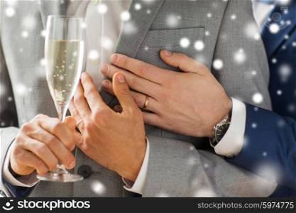 people, celebration, homosexuality, same-sex marriage and love concept - close up of happy married male gay couple in suits drinking sparkling wine from glass on wedding over snow effect