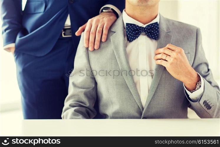 people, celebration, homosexuality, same-sex marriage and love concept - close up of male gay couple with wedding rings on putting hand on shoulder