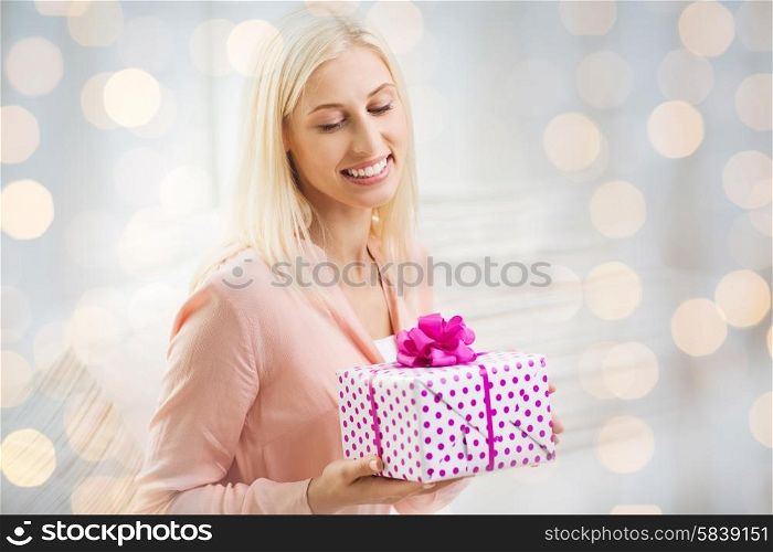 people, celebration, valentines day and birthday concept - smiling young woman with gift box over holidays lights background