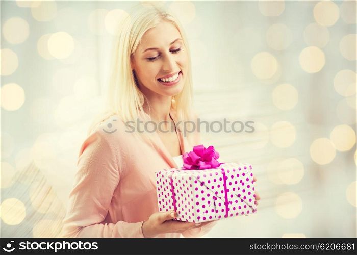 people, celebration, valentines day and birthday concept - smiling young woman with gift box over holidays lights background