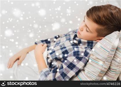 people , childhood and rest concept - little boy sleeping at home over snow