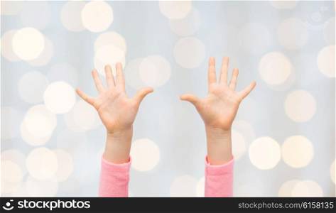 people, childhood, gesture and body parts concept - close up of little child hands raised up over holidays lights background