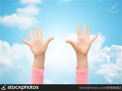 people, childhood, gesture and body parts concept - close up of little child hands raised up over blue sky and clouds background
