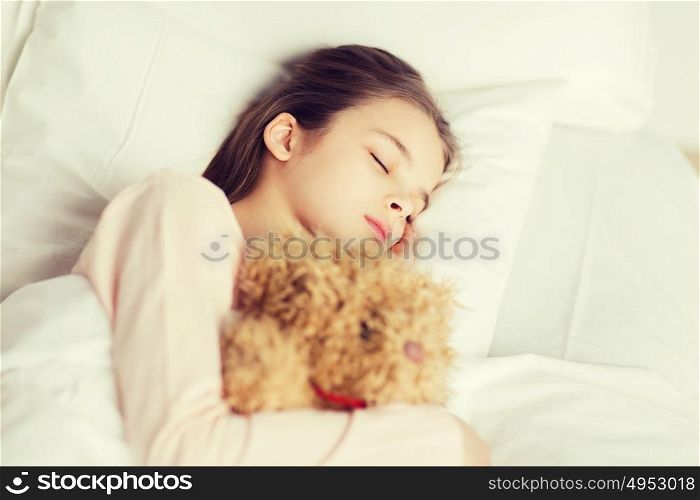 people, childhood, rest and comfort concept - girl sleeping with teddy bear toy in bed at home. girl sleeping with teddy bear toy in bed at home