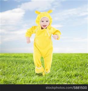 people, children, achievement and happiness concept - happy baby in yellow suit making first steps over blue sky and grass background
