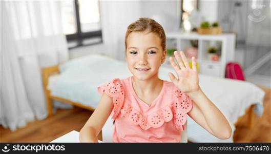 people, children and gestures concept - happy little girl waving hand at home. happy little girl waving hand at home