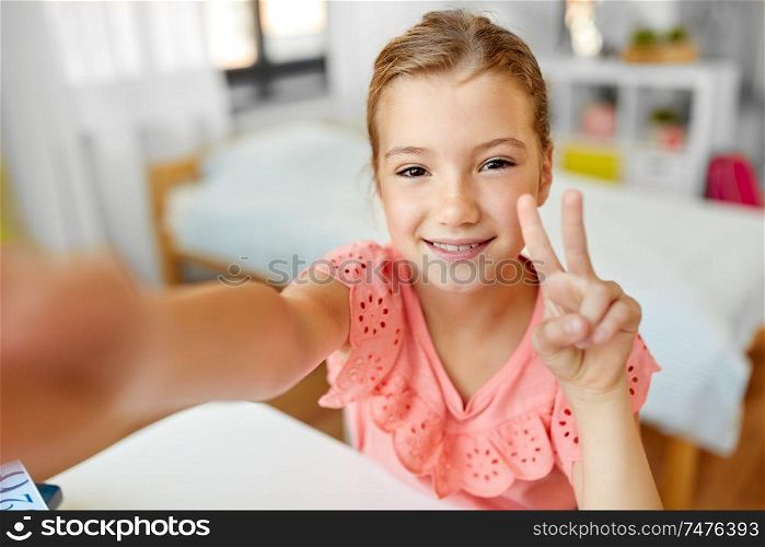 people, children and technology concept - girl taking selfie at home. happy girl taking selfie at home
