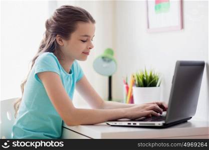 people, children and technology concept - girl typing on laptop computer at home. girl typing on laptop at home