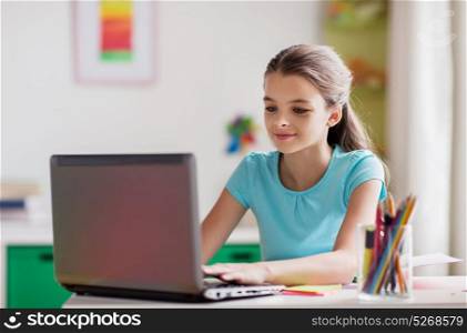 people, children and technology concept - girl typing on laptop computer at home. girl typing on laptop at home