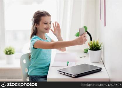 people, children and technology concept - girl with laptop computer and smartphone taking selfie or having video call at home
