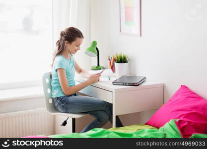 people, children and technology concept - girl with laptop computer and smartphone texting at home. girl with laptop and smartphone texting at home