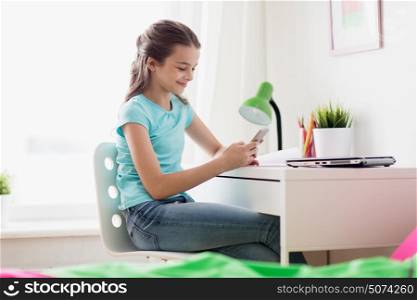 people, children and technology concept - girl with laptop computer and smartphone texting at home. girl with laptop and smartphone texting at home