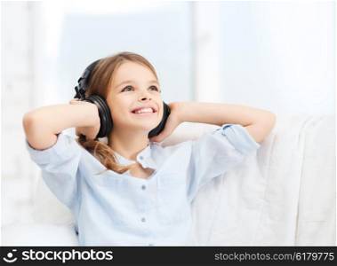 people, children and technology concept - smiling girl with headphones listening to music at home