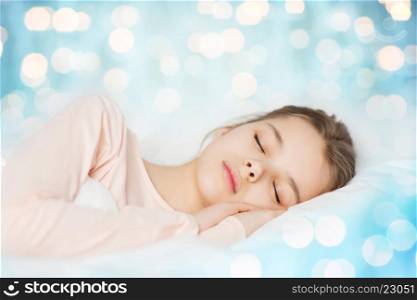 people, children, dreaming, rest and comfort concept - girl sleeping in bed over blue lights background
