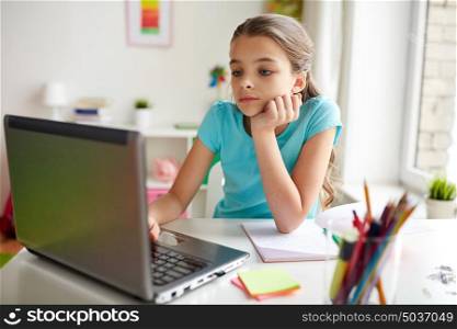 people, children, education and learning concept - bored girl with laptop computer and notebook doing homework at home. bored girl with laptop and notebook at home